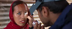 A health worker checks a woman's eyes for signs of trachoma.