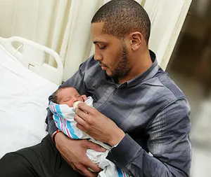 A father holds a newborn baby in a hospital room