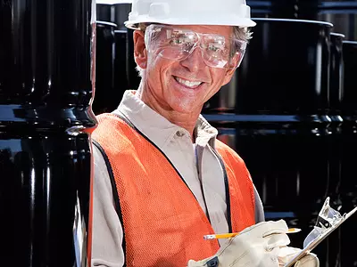 A male worker in a hard hat takes notes in a chemical plant