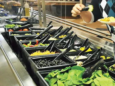 A customer selects food from a salad bar