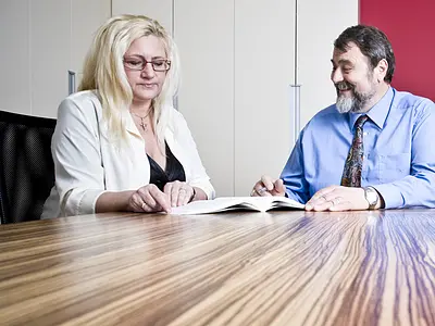 two people review documents in a conference room