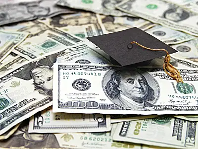 Graduation cap resting on assorted U.S. dollar bills, symbolizing education financing, on a money-covered surface.