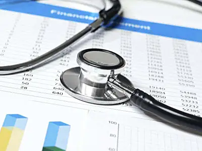 Stethoscope resting on financial documents with charts and graphs in a medical setting.