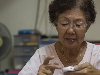 Senior woman monitors her diabetes by checking her blood sugar level