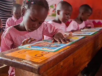 Ugandan schoolchildren practice reading in a classroom.