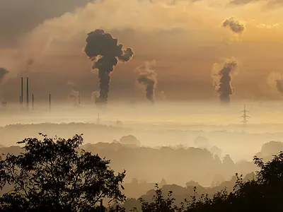 The sun rises over a landscape with factories and smokestacks.