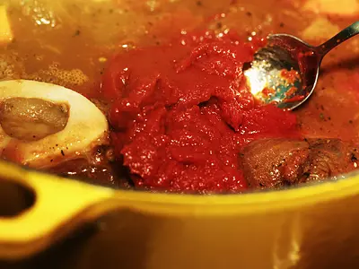A closeup of a spoon in a simmering pot of beef stew.