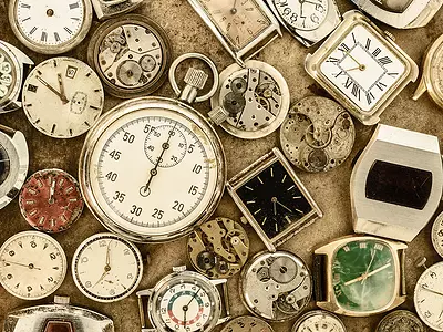 A collection of antique clocks, watches, stopwatches, and clock parts.
