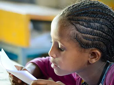 An Ethiopian girl reads from a paper in her classroom.
