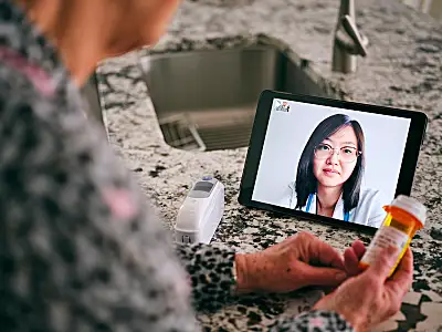 A senior woman meets with her doctor via a teleconferencing app on her phone.