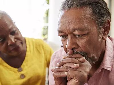 A senior Black couple with serious facial expressions.