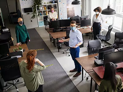 Workers use masks and social distancing while sharing office space during a pandemic.