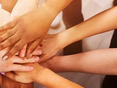 A group of people stack their hands on top of each other showing togetherness