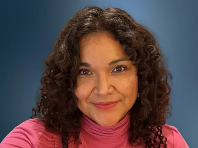 Headshot of Daniela Pineda smiling against a blue background