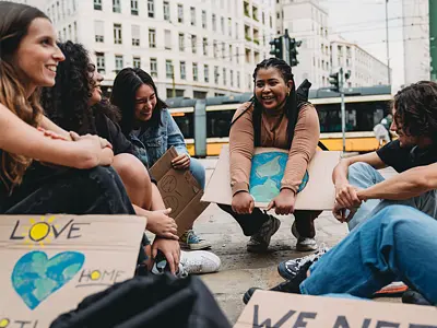 Photo of a group of young climate activists in a city sitting and talking with signs