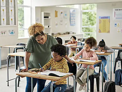 female teacher assisting male student at desk