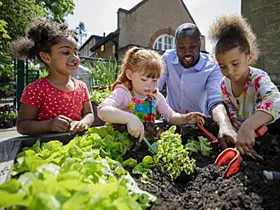 Photo of preschool students and a teacher working in a garden.