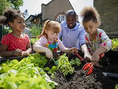 Photo of preschool students and a teacher working in a garden.