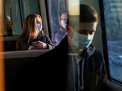 Woman wearing a protective medical mask staring out the window of a bus