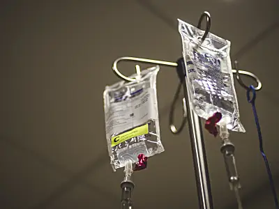 Two IV bags handing from metal pole. 