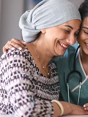 Photo of a patient in a headwrap and a medical practitioner smiling together