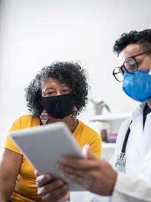 Photo of masked doctor and patient reviewing a survey