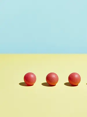 Illustration of a row of red balls on a yellow and blue background. One ball is missing from the row.