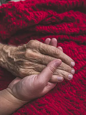 Photo of a caregiver holding an elderly patient's hand.