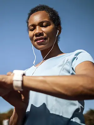 Photo of a runner checking a smartwatch and wearing ear buds.