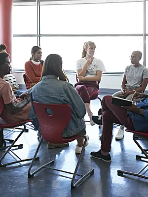 Photo of a group of young adults having a discussion in a circle.