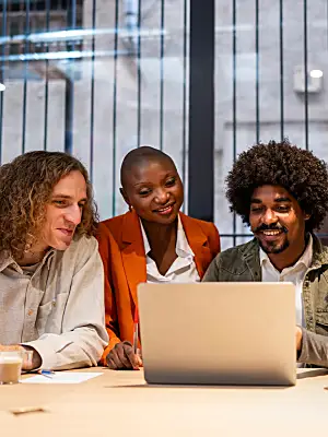 Photo of four colleagues gathered around a laptop.