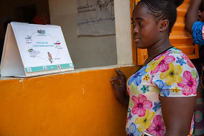 Woman looks at an educational malaria sign