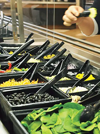 A customer selects food from a salad bar