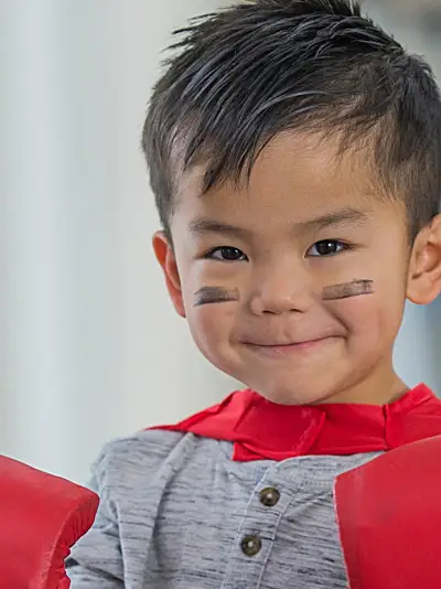 A little boy wears boxing gloves