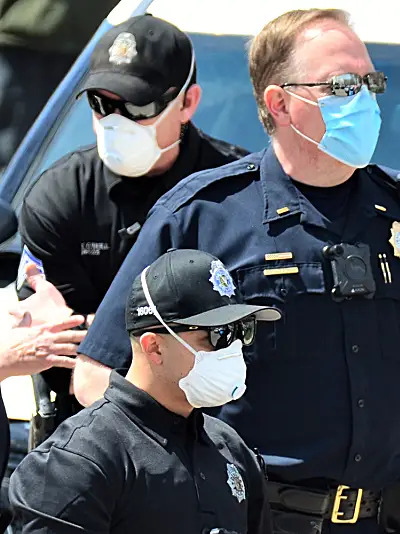 a group of police officers on scene are all wearing protective masks due to the COVID-19 pandemic