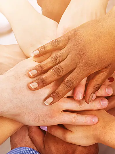 A group of people stack their hands on top of each other showing togetherness