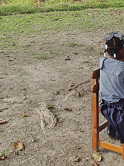 Child at desk outside with teacher