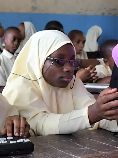 Girls with visual impairments practice reading in a classroom in Zanzibar.