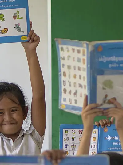 School girl holding reading book above her head