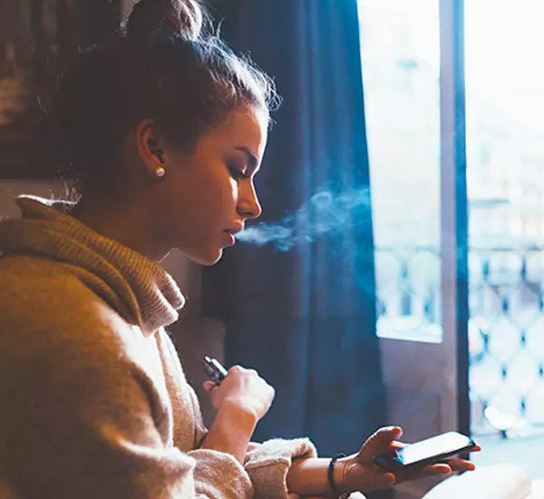 Teen vaping while using mobile phone