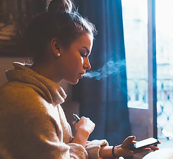 Teen vaping while using mobile phone