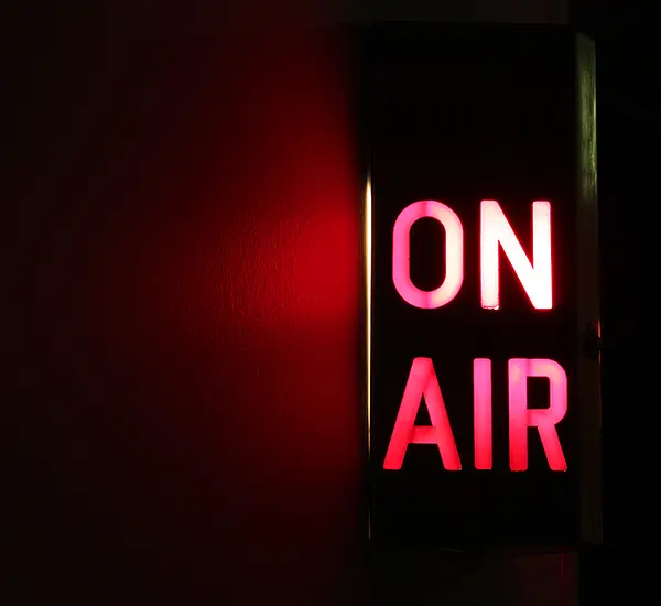 A lighted, red "On Air" sign on a black background.