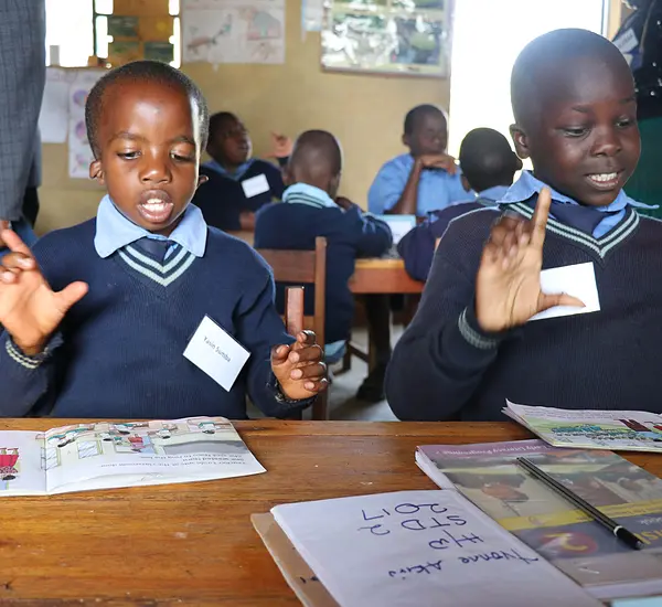Kenyan children use sign language during a reading class.