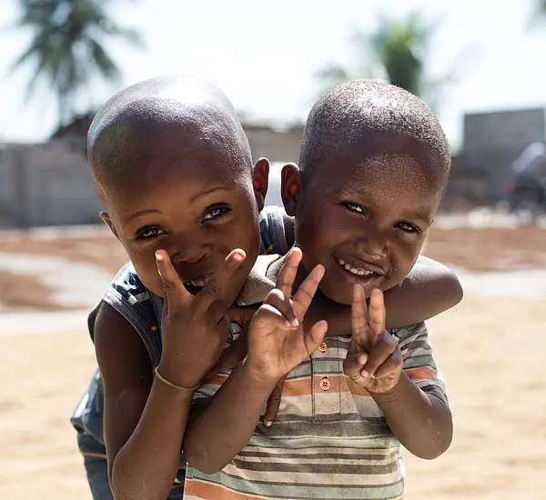 Photo of two children smiling giving peace signs