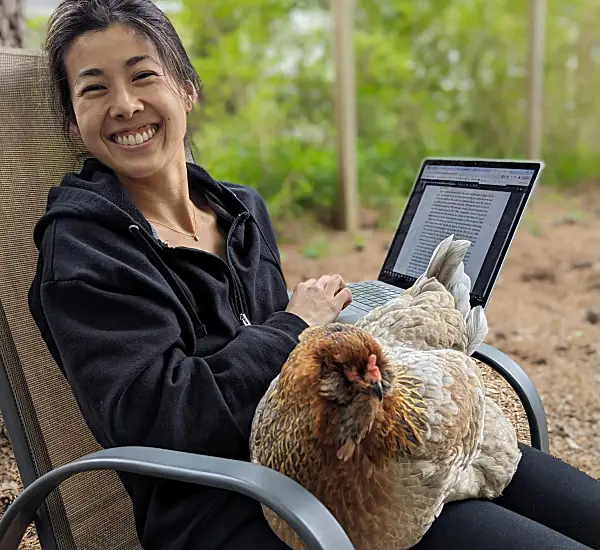 Candise holding her laptop with a chicken on her lap