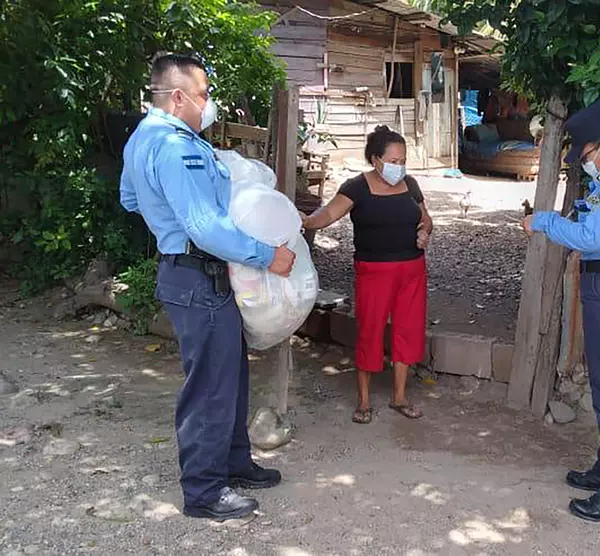 Police officers in Honduras hand out bags of groceries as part of a COVID-19 relief effort.