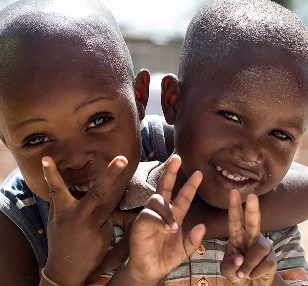 Two Haitian children hug and smile in a courtyard.