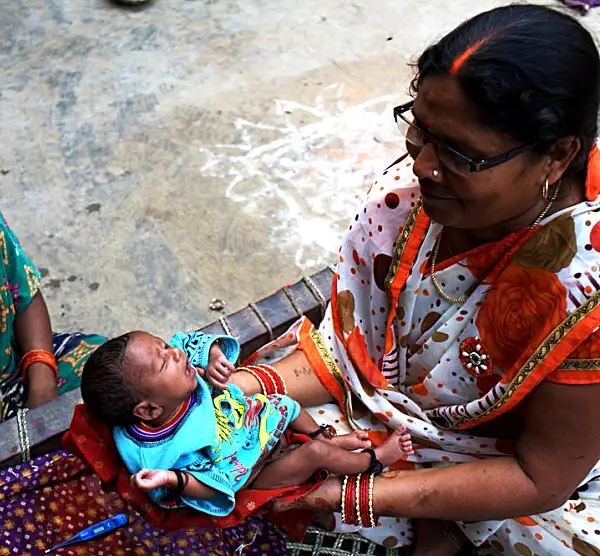 An accredited social health activist visits a mother and child at their home in an Indian village.