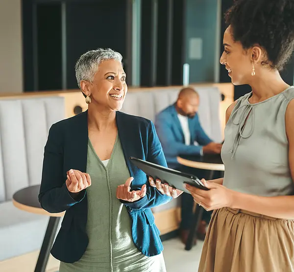 Photo of two women of color talking and smiling in an office