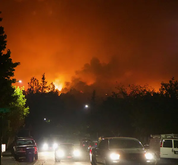 cars on a road with forest fires in the distance.